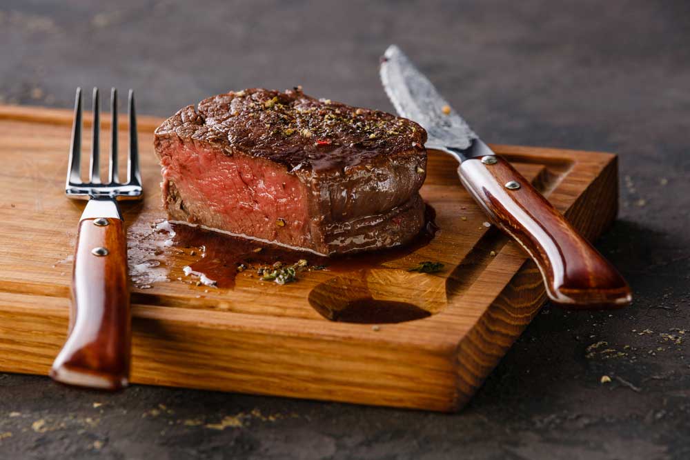 Filet mignon cut on a cutting board with a knife