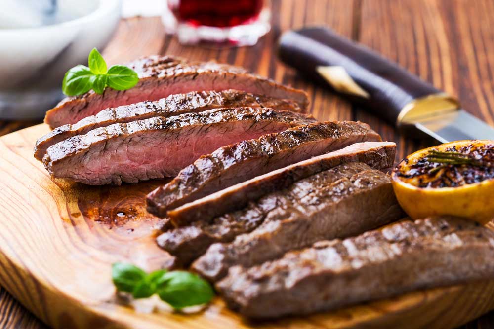 sliced medium rare flank steak on a cutting board