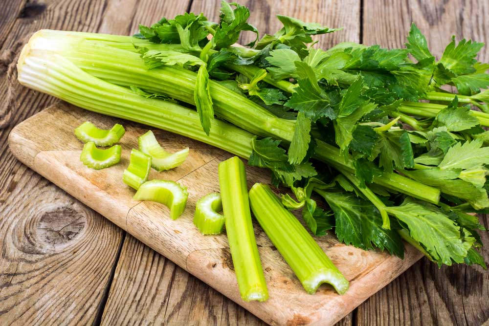 head of celery with some cut and chopped on a cutting board