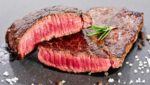 medium rare steak cut in half on slate serving platter