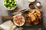 Pork chops on cutting board surrounded by side dishes and spices