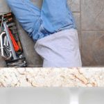 Man under sink with tools