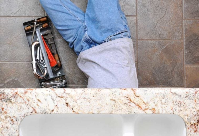 Man under sink with tools