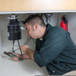 Man under sink repairing garbage disposal