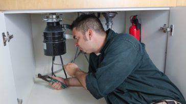 Man under sink repairing garbage disposal