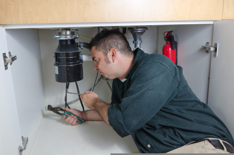 Man under sink repairing garbage disposal