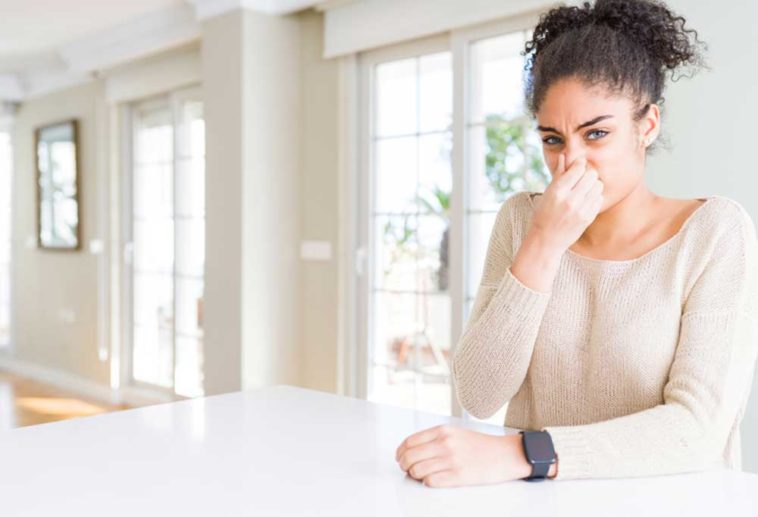 Woman holding nose sitting at kitchen island