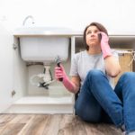 woman sitting on floor next to leaking garbage disposal