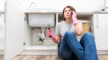 woman sitting on floor next to leaking garbage disposal