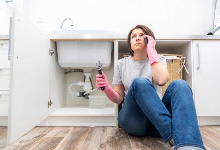 woman sitting on floor next to leaking garbage disposal