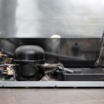 back view of a refrigerator with compressor and drip pan