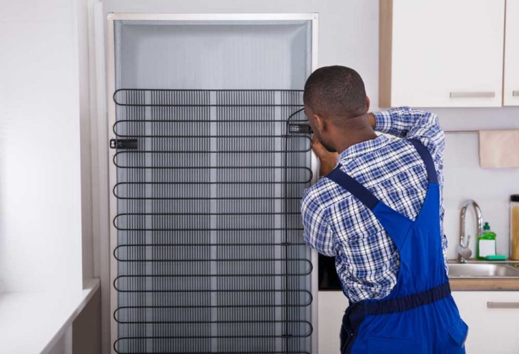 Man fixing coils on fridge