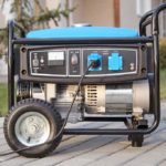 Black and blue generator on wheels sitting on a brick driveway