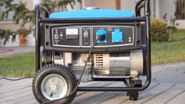 Black and blue generator on wheels sitting on a brick driveway
