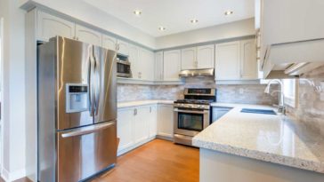 Stainless steel fridge with a dent in the door in a clean kitchen
