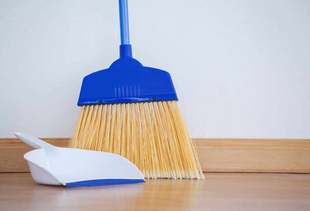 Broom and dust pan leaning against a wall