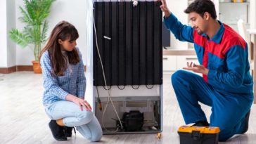 Man and woman kneeling behind broken fridge