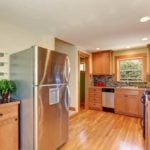 Wood themed kitchen with a stainless steel fridge