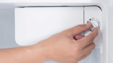 Hand turning dial to refrigerator thermostat