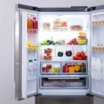 Open fridge full of food on a grey wall