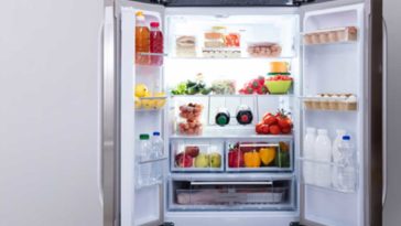Open fridge full of food on a grey wall
