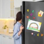 Woman looking into a stainless steel fridge with magnets on the front