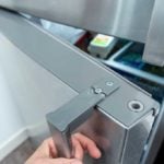 Hand pulling fridge handle that is cracked on the top