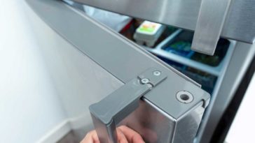 Hand pulling fridge handle that is cracked on the top