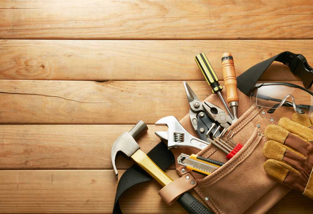 Tool belt laying on wooden deck with variety of tools sticking out of the belt