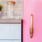 Partial view of the door of a retro pink fridge against a kitchen counter