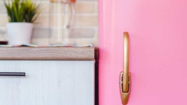 Partial view of the door of a retro pink fridge against a kitchen counter