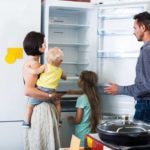 Woman, Man, and children looking at the inside of a refrigerator on a showroom floor