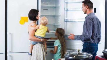 Woman, Man, and children looking at the inside of a refrigerator on a showroom floor