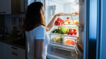 woman looking in fridge with door open and light on