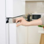 Close up of hand opening white fridge door