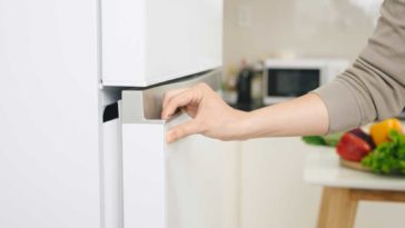Close up of hand opening white fridge door
