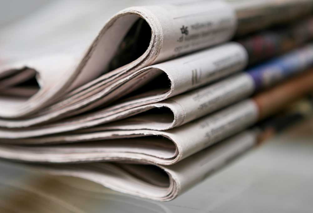 Stack of folded news papers on a glass table.