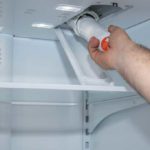 hand installing a water filter in a fridge