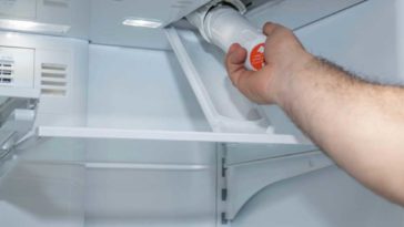 hand installing a water filter in a fridge