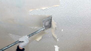 close up of ceiling texture being scraped off with a tool on a pole