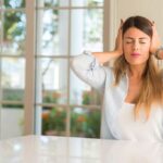 Woman sitting at counter holding hands over ears