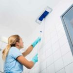 Woman with a rectangle dust mop cleaning a white ceiling