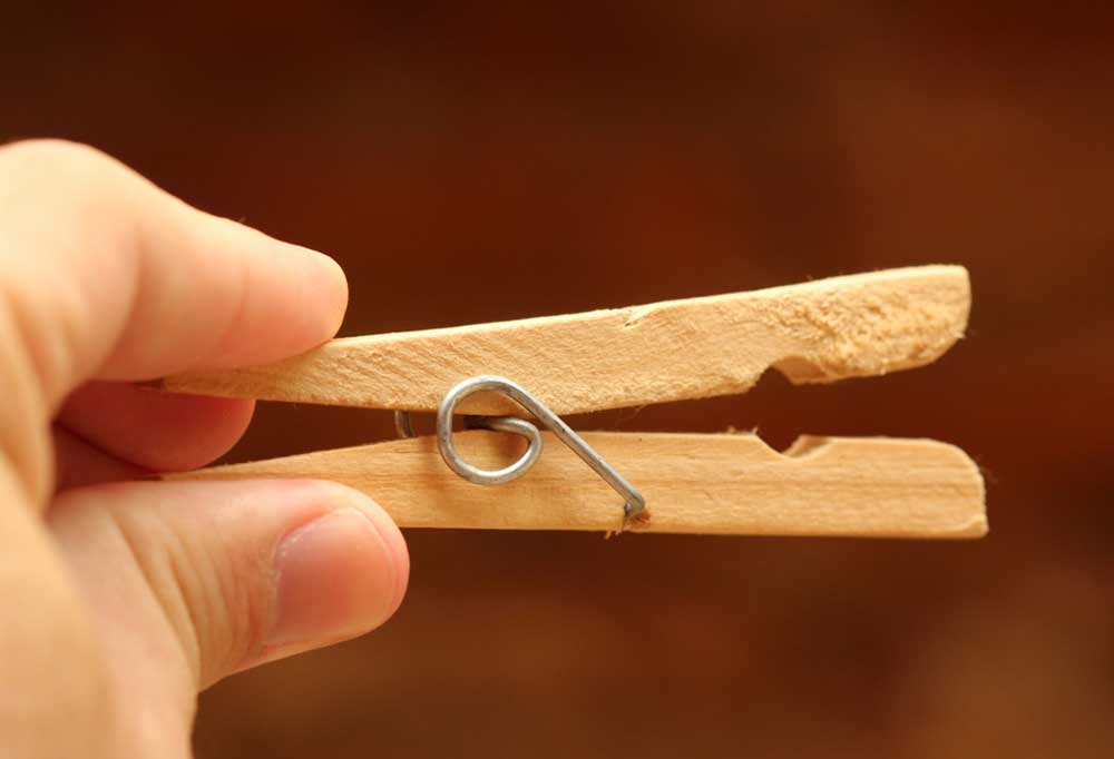 Fingers pinching a clothespin open