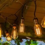 Edison style string lights attached to a raw beam under an unfinished roof