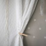 Hung fabric pulled back with a clothes pin on a polka dot wall