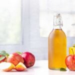 Apple Cider Vinegar in a non-labeled bottle on a table with apples