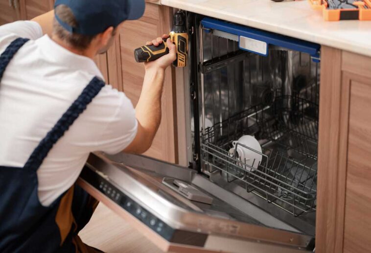 Repair man removing screws that are holding in the dishwasher