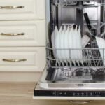 Dishwasher full of dirty dishes standing open with water in the bottom