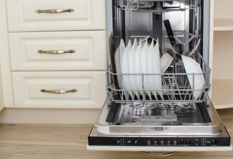 Dishwasher full of dirty dishes standing open with water in the bottom