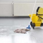 Mop and yellow bucket resting on grey concrete floors